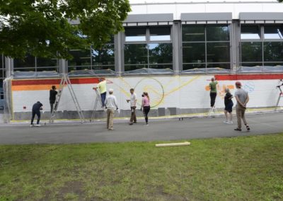 Schüler besprühen eine Wand mit Graffiti